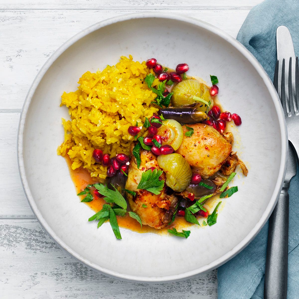 Färggrann mat, saffransris, kyckling, granatäppelkärnor, på en vit tallrik