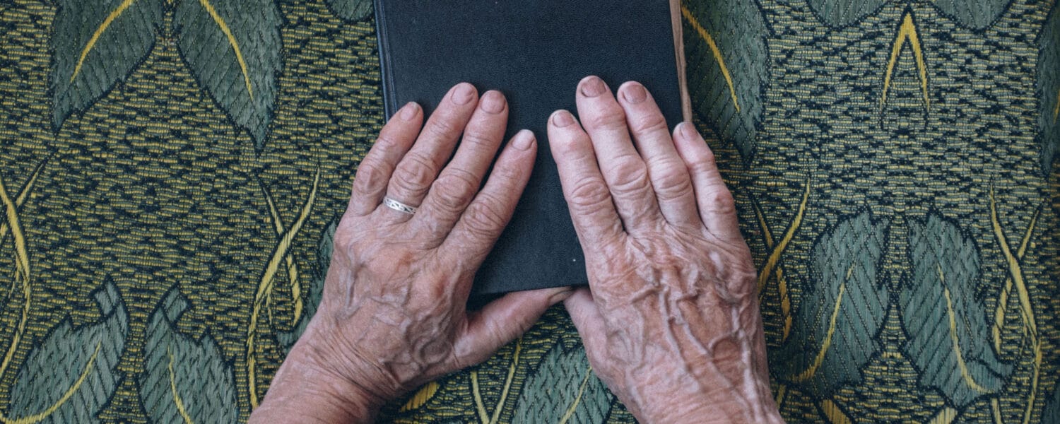 En åldrings händer ovanpå en bibel